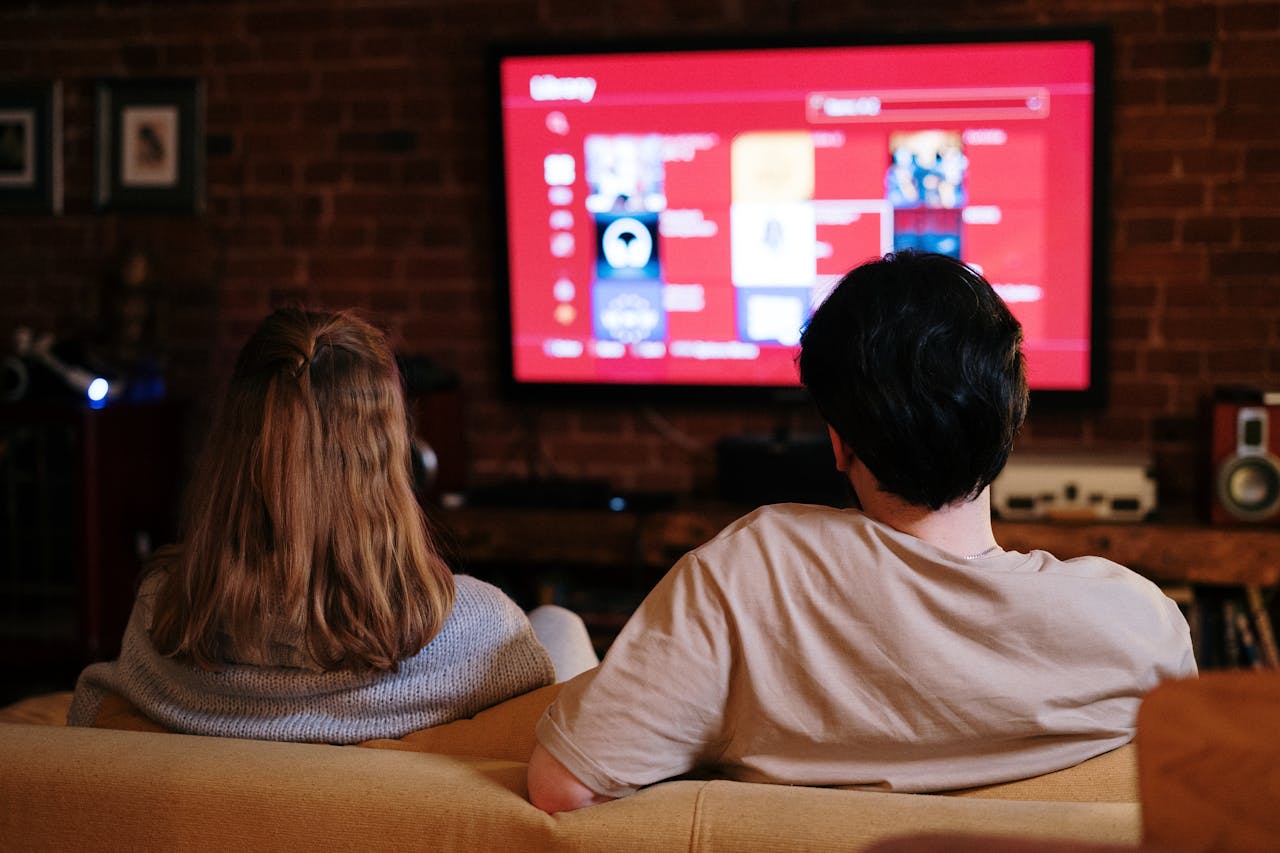 vision A couple enjoys streaming shows on a large TV in a cozy, brick-walled living room.